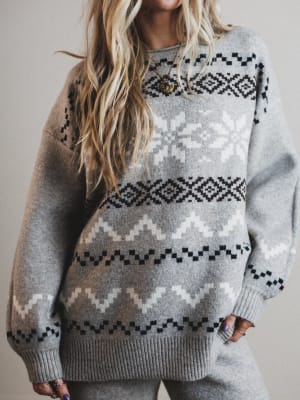 Person wearing a gray sweater with a pattern, against a neutral background