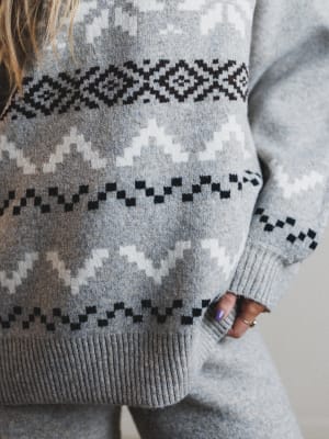 Gray sweater with a black and white pattern worn by a person.