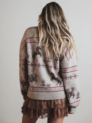 Person wearing a patterned sweater with ruffled hem on a plain background