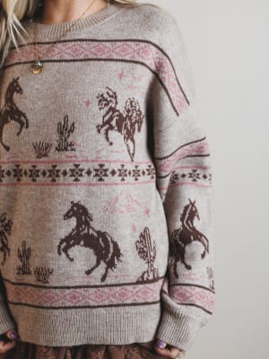 Sweater with horse and cactus pattern worn by a person