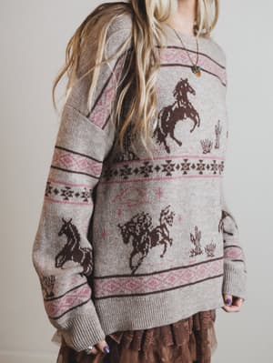 Person wearing a sweater with horse patterns on a plain background