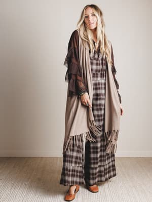 Woman wearing a long, plaid dress with a vest in a minimalistic setting
