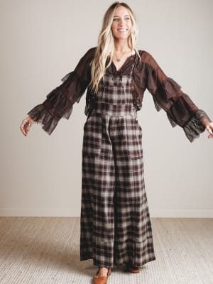 Woman wearing a plaid dress with a brown blouse in a minimal indoor setting