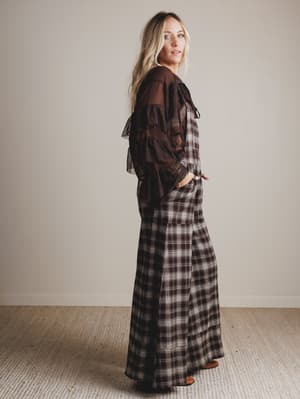 Woman wearing a plaid jumpsuit with a brown background
