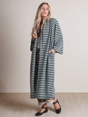 Woman wearing a long, striped coat against a plain background