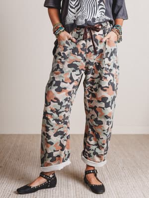 Person wearing camouflage pants with a neutral background