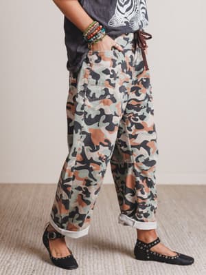 Person wearing camouflage pants with a neutral background