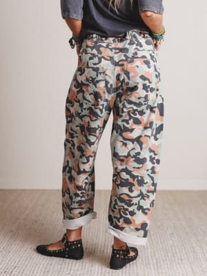 Person wearing camouflage pants with a neutral background