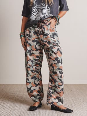 Person wearing camouflage pants with a neutral background
