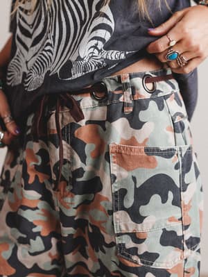 Person wearing a zebra-patterned top and camouflage pants with a neutral background