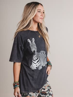 Woman wearing a black t-shirt with a zebra graphic on a plain background