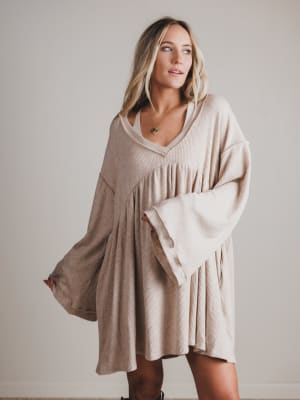 Woman wearing a beige dress against a plain background