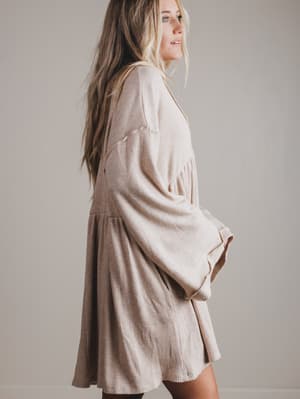 Woman wearing a beige dress against a plain background