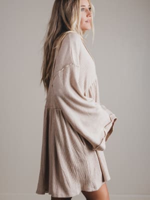 Woman wearing a beige dress against a plain background