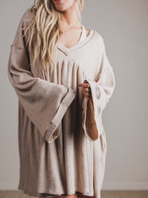 Woman wearing a beige dress with bell sleeves against a plain background