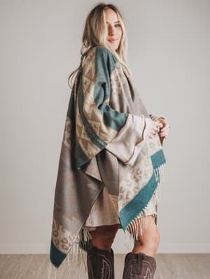 Woman wearing a patterned shawl with fringes against a plain background