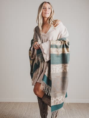 Woman wrapped in a patterned shawl with a neutral background