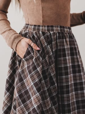 Plaid skirt worn with a brown top against a neutral background