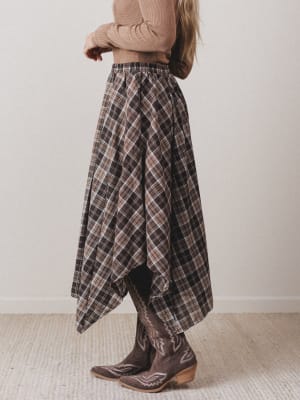Person wearing a plaid skirt and brown boots indoors.