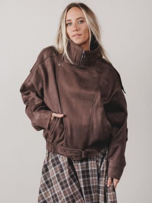 Person wearing a brown jacket with a plain background