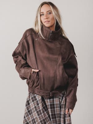 Person wearing a brown jacket with a plain background