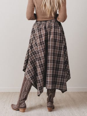 Person wearing a plaid skirt and patterned pants against a plain background