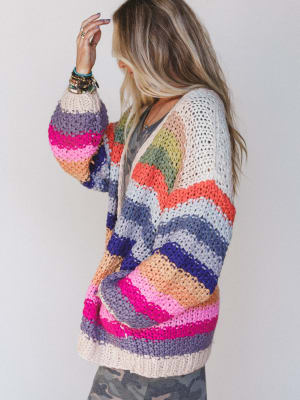 Woman wearing a colorful crochet cardigan against a plain background