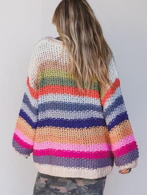 Person wearing a colorful striped sweater against a plain background