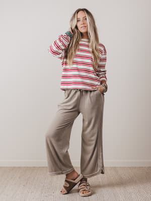Woman wearing a red and white striped shirt and beige pants against a plain background