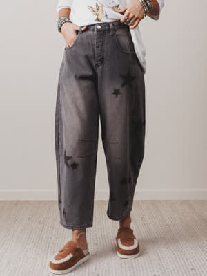 Person wearing dark gray distressed jeans with a plain background