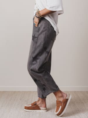 Person wearing gray pants and brown shoes on a neutral background