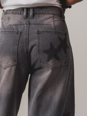 Person wearing dark gray jeans on a plain background