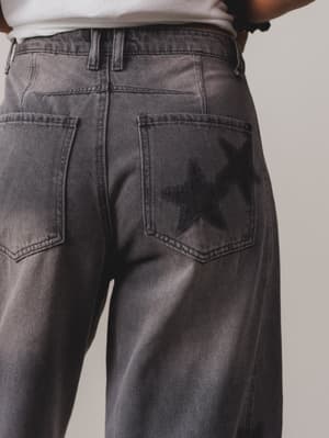 Person wearing dark gray jeans on a plain background