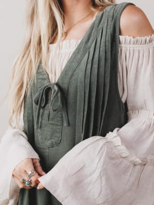 Person wearing a green dress over a white top with a neutral background