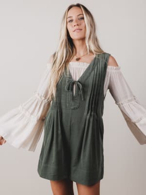 Woman wearing a green dress with white sleeves against a plain background
