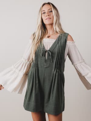 Woman wearing a green dress with white sleeves against a plain background
