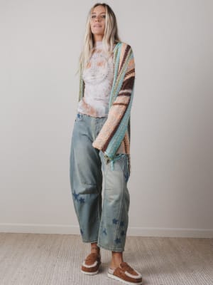 Woman wearing a colorful cardigan, patterned shirt, and jeans with star designs.