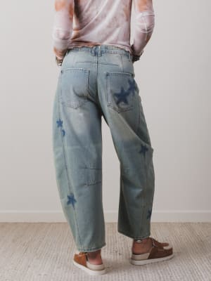 Person wearing light blue jeans with star patterns, standing against a plain background.