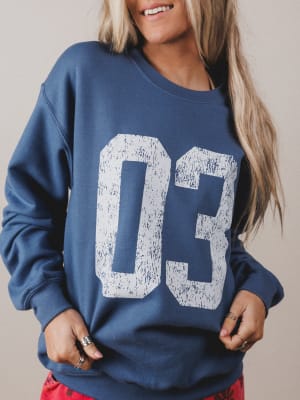 Person wearing a blue sweatshirt with 'DC' printed on it against a neutral background