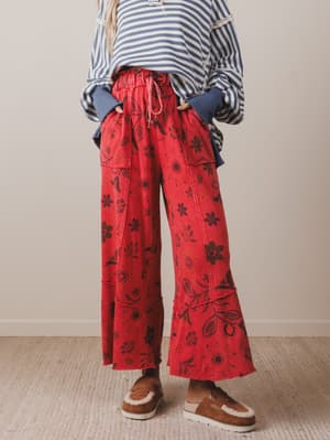 Person wearing red floral pants and a striped shirt against a neutral background