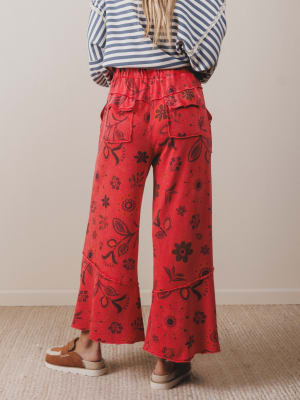 Person wearing red floral-patterned pants and a striped shirt against a neutral background