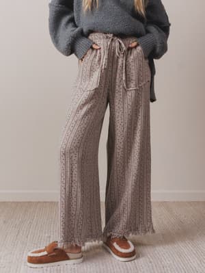 Person wearing patterned pants and a dark sweater on a neutral background