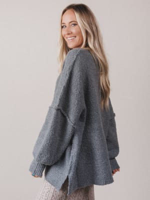 Woman wearing a gray knitted cardigan against a plain background