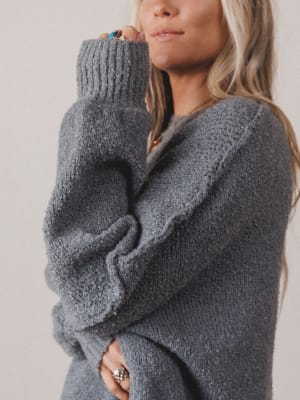 Person wearing a gray oversized sweater against a plain background