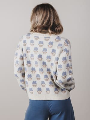 Person wearing a sweater with a floral pattern on a plain background