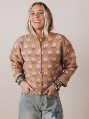 Person wearing a brown floral-patterned cardigan against a plain background