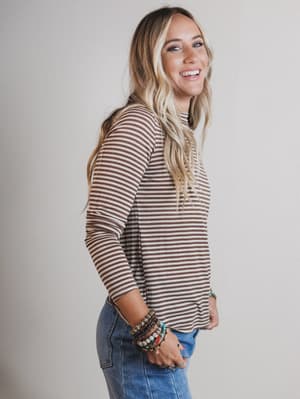 Woman wearing a striped long-sleeve top and jeans against a plain background