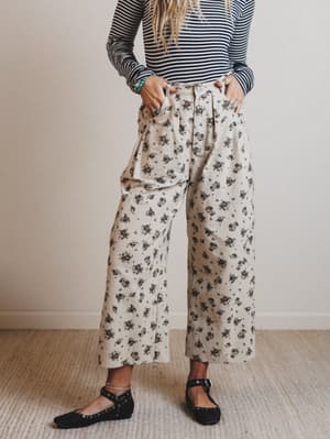 Person wearing a striped shirt and floral pants in a minimal indoor setting
