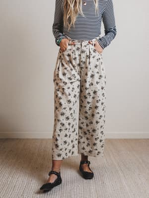 Person wearing a striped top and floral pants on a plain background
