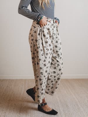 Person wearing floral pants and a striped shirt against a plain background